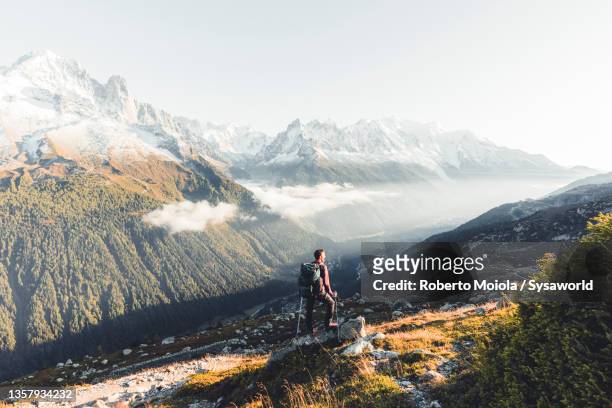hiker man looking at mont blanc massif in the mist - mont blanc massif stock-fotos und bilder