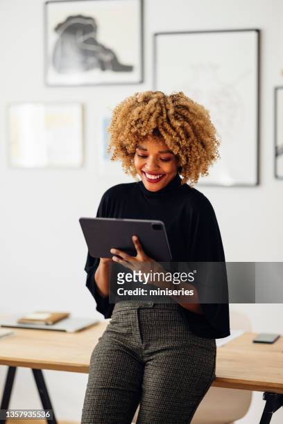 feliz mujer de negocios sentada en su escritorio usando su tableta - laptop fotografías e imágenes de stock