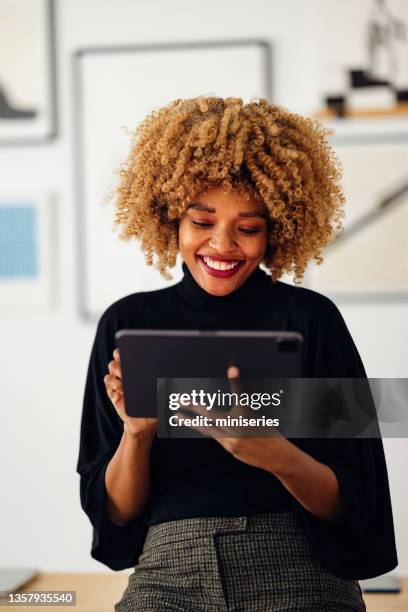 happy businesswoman sitting on her desk using her tablet - mid adult stock pictures, royalty-free photos & images