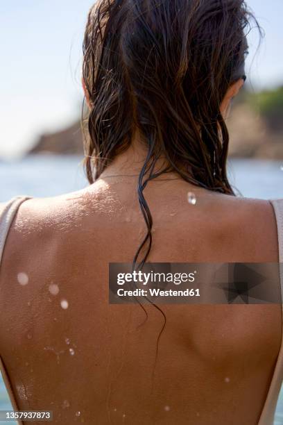 young woman with wet hair and back at beach - nasses haar stock-fotos und bilder