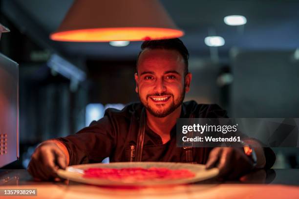 chef keeping food plate below pendant light in restaurant kitchen - nordafrikanischer abstammung stock-fotos und bilder