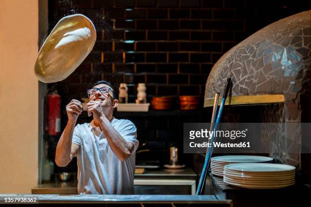 pizza maker spinning dough in kitchen - pizza toss foto e immagini stock
