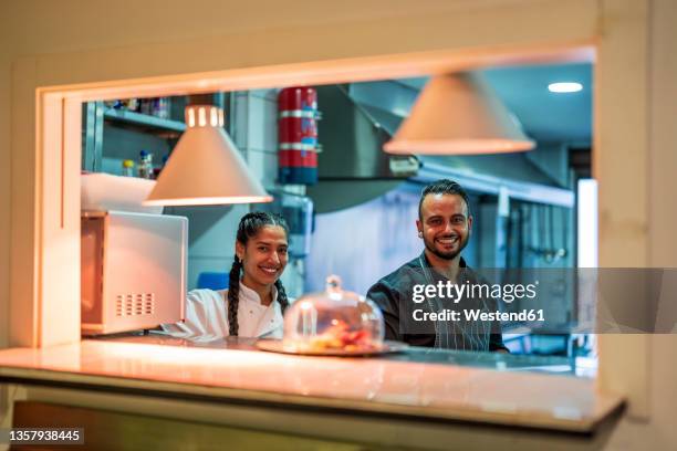 smiling chef and trainee in commercial kitchen at restaurant - kochlehrling stock-fotos und bilder