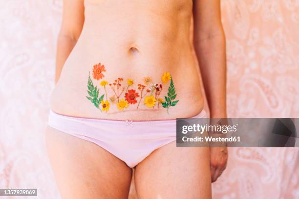 woman in underwear showing caesarean scar with flowers tattoo - female navel ストックフォトと画像