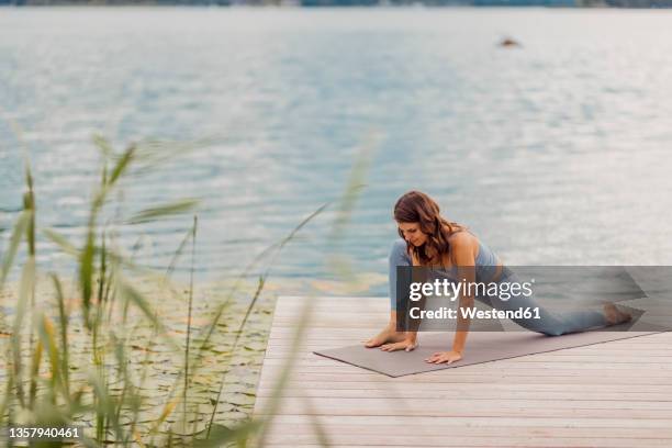 active woman practicing yoga on jetty - kärnten am wörthersee stock pictures, royalty-free photos & images