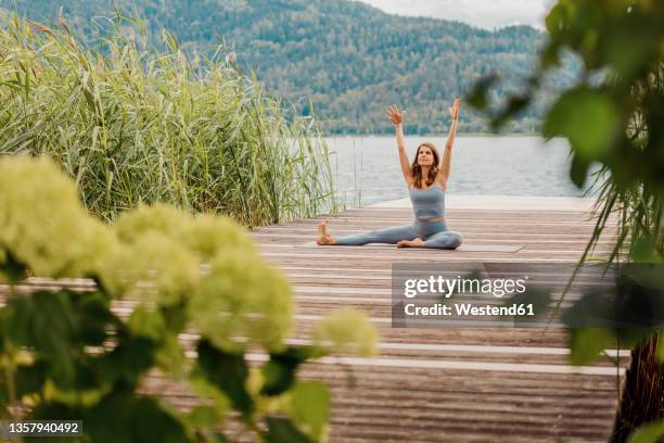 woman with arms raised exercising on jetty - kärnten am wörthersee stock pictures, royalty-free photos & images