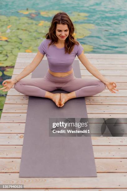 brunette woman meditating on jetty - kärnten am wörthersee stock pictures, royalty-free photos & images