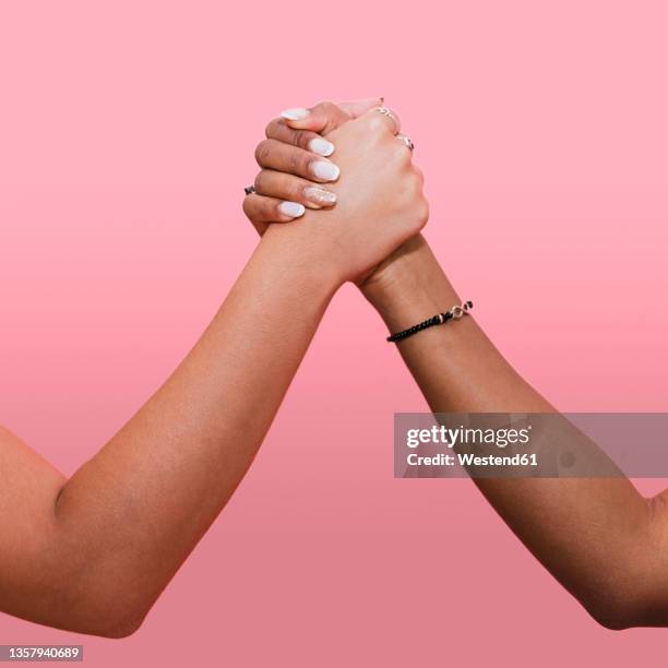 young woman holding hands with lesbian couple against pink background - black and white hands fotografías e imágenes de stock