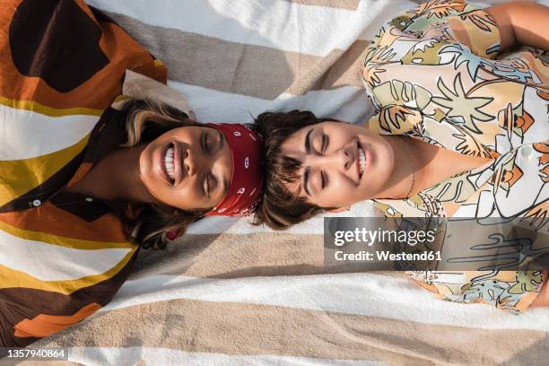 smiling women lying on picnic blanket at beach - manta de picnic fotografías e imágenes de stock