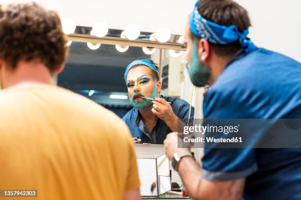 bearded man doing drag queen makeup by friend - drag queens stock pictures, royalty-free photos & images