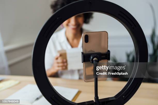 a mixed-race woman's smartphone being put in the focus while she is recording a video - net promoter stock pictures, royalty-free photos & images