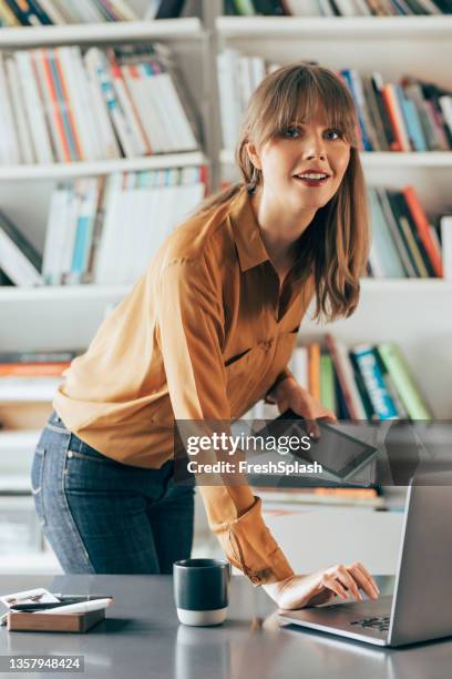 porträt einer lächelnden geschäftsfrau, die auf einem laptop arbeitet - librarian stock-fotos und bilder