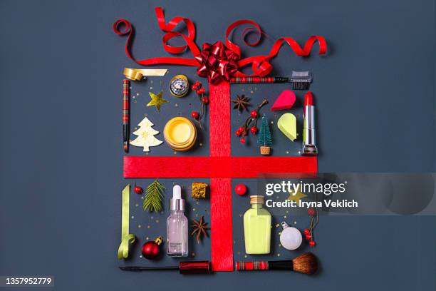 christmas objects and beauty products laid out in the shape of a gift box with red ribbon. - christmas beauty stockfoto's en -beelden