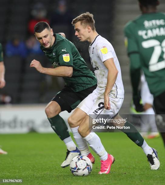 James Wilson of Plymouth Argyle looks on as Scott Twine of Milton Keynes Dons controls the ball during the Sky Bet League One match between Milton...