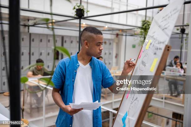 junger mann schreibt einen businessplan auf einem whiteboard im büro - internship marketing stock-fotos und bilder