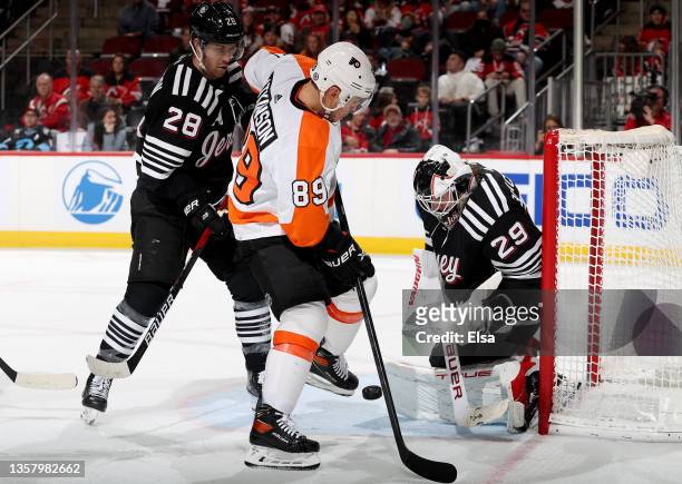 Mackenzie Blackwood of the New Jersey Devils stops a shot by Cam Atkinson of the Philadelphia Flyers as Damon Severson of the New Jersey Devils...