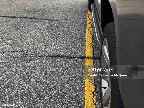 partial view of car parked with wheels touching yellow parking line - yellow line stockfoto's en -beelden