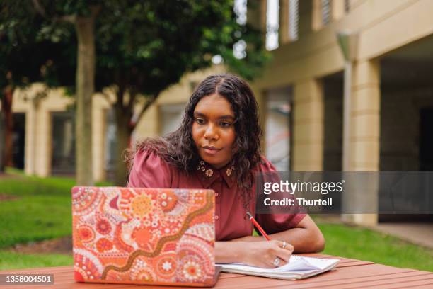 female aboriginal australian student working on laptop - aboriginal stockfoto's en -beelden