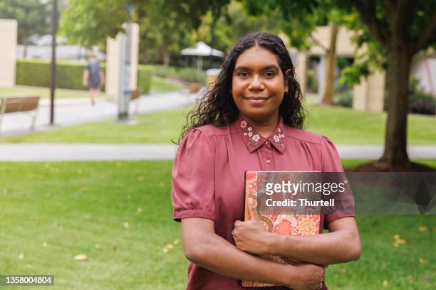 estudiante aborigen australiana sosteniendo una computadora portátil - etnia fotografías e imágenes de stock