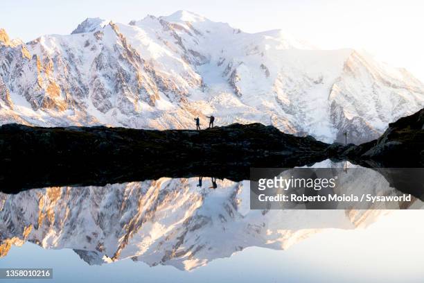 hikers watching mont blanc at sunset from lake chesery - mont blanc sunset stock-fotos und bilder