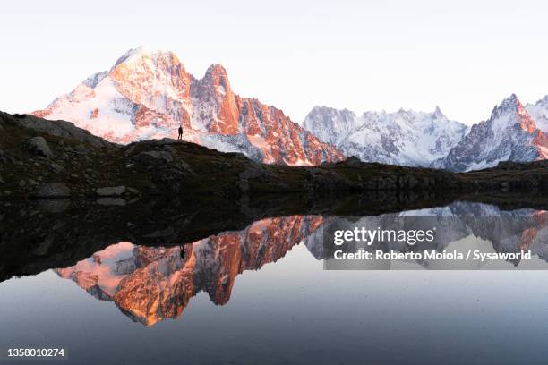 person admiring mountains from lake chesery, france - lac reflection lake photos et images de collection