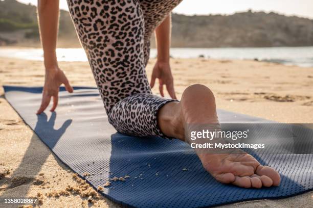 healthy female practicing morning routine stretches on the beach, yoga - leopard print stock pictures, royalty-free photos & images