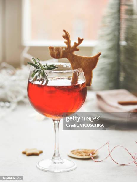 seasonal red winter drink in wine glass with rosemary and reindeer biscuit on kitchen table at window background with natural light - reindeer food stock pictures, royalty-free photos & images