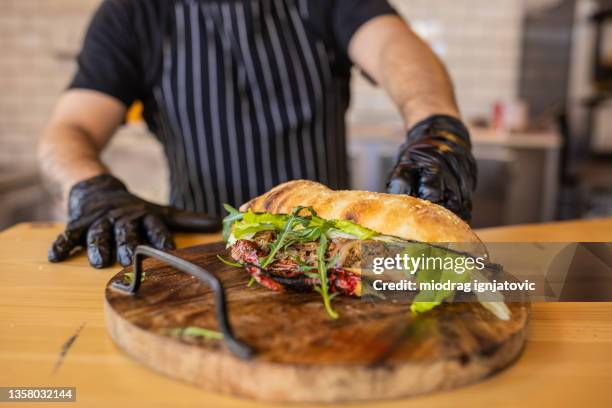 unrecognizable chef, serving the juicy beef sandwich - roast beef sandwich stock pictures, royalty-free photos & images