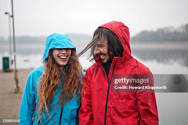 couple enjoying rainstorm - raincoat stock pictures, royalty-free photos & images