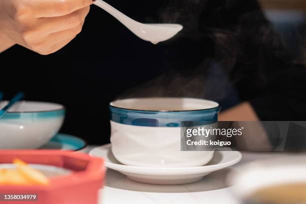 lady drinking a chinese-style health soup with a spoon - chinese soup photos et images de collection