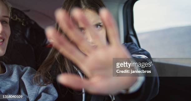 pas de photos s’il vous plaît! jeune femme assise dans une voiture, couvrant l’objectif de la caméra. pov du pilote - covered car photos et images de collection