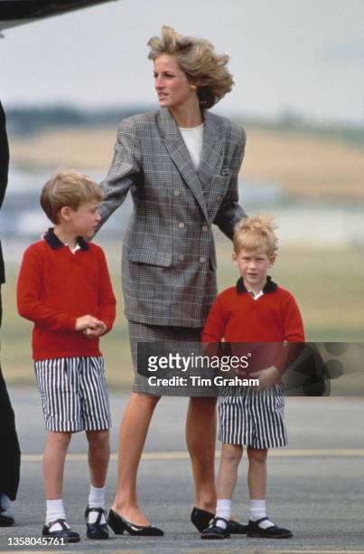 British Royal Diana, Princess of Wales , wearing a Glen Plaid suit, and her sons Prince William and Prince Harry, both wearing red sweaters and...