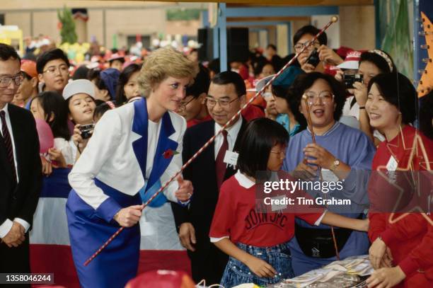 British Royal Diana, Princess of Wales , wearing a blue-and-white Catherine Walker suit and a Remembrance poppy, holding a thin striped pole while...