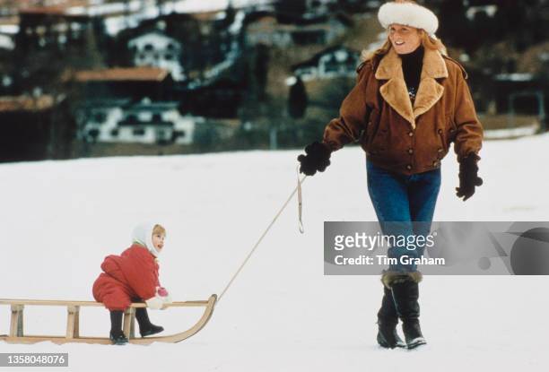 British Royals Sarah, Duchess of York, wearing a brown leather jacket with a white fur headband, with Princess Beatrice, wearing a red ski suit, on a...
