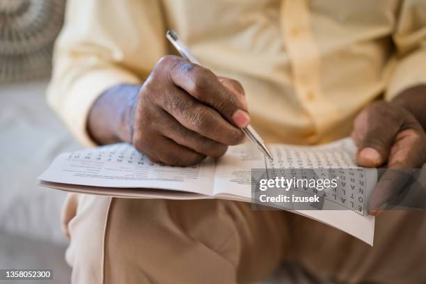 elderly man solving puzzle at home - kruiswoordpuzzel stockfoto's en -beelden