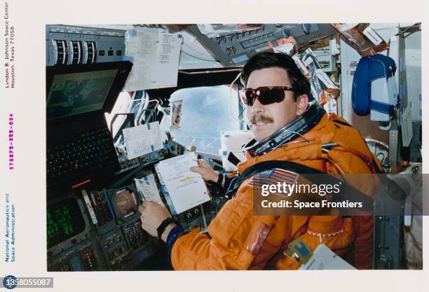 American NASA astronaut Scott J Horowitz wearing his partial-pressure launch-and-entry suit communicates with ground control from the pilot's station...
