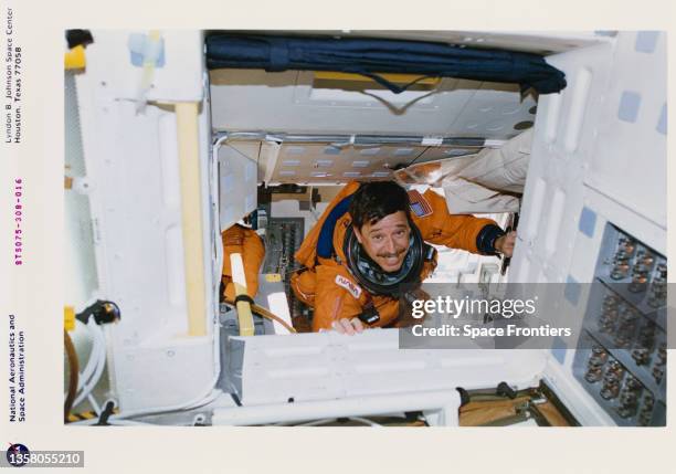 American NASA astronaut Scott J Horowitz still wearing his partial-pressure launch-and-entry suit moves down into the mid-deck area after unbelting...