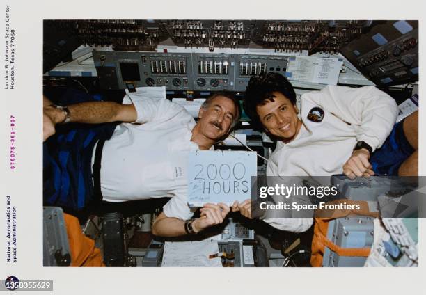 American NASA Jeffrey A Hoffman and Costa Rican-American NASA astronaut Franklin R Chang-Diaz hold up a sign to celebrate the fact that each has...