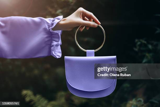 a woman's hand holds a purple-red tint color 2022 handbag in her hand - lila handtasche stock-fotos und bilder