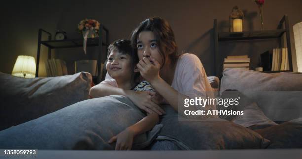 sister watching scare movie with brother at night - family watching television stock pictures, royalty-free photos & images