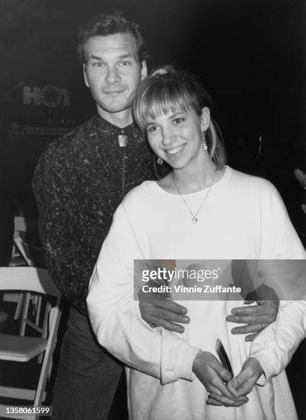 American actor, singer and dancer Patrick Swayze standing behind American singer-songwriter Debbie Gibson, holding her around the waist, as they...