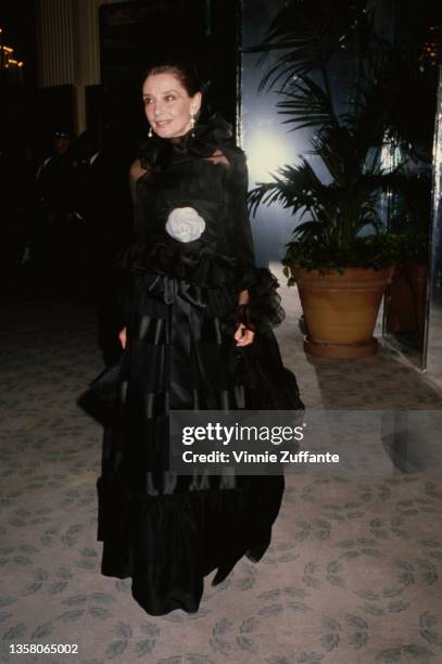 British actress Audrey Hepburn , wearing a black evening gown with a floral motif attends the American Film Institute ceremony honouring Gregory...