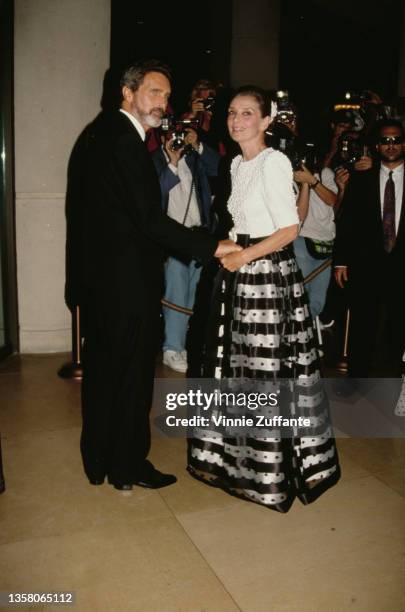 Dutch television actor Robert Wolders and British actress Audrey Hepburn , wearing a long hooped skirt with a white short-sleeved top, attend the 7th...