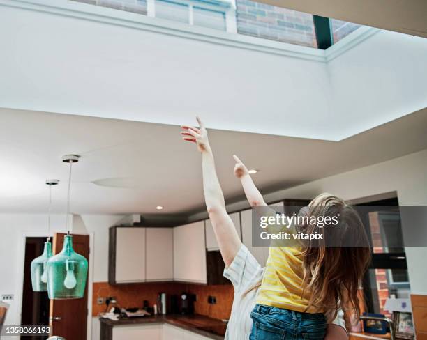 mother and daughter looking through skylight - glass ceiling stock pictures, royalty-free photos & images