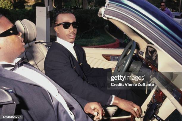 American rapper and dancer MC Hammer driving in a car with an passenger, circa 1990.