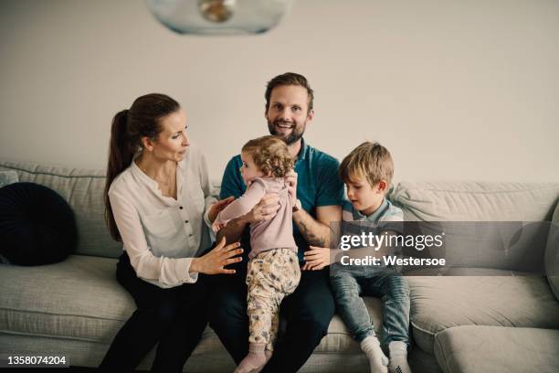 family with four people sitting in sofa - nordiska bildbanksfoton och bilder