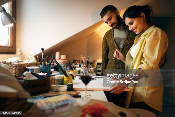 caucasian creative female artist, explaining her art to her boyfriend - house for an art lover stock pictures, royalty-free photos & images