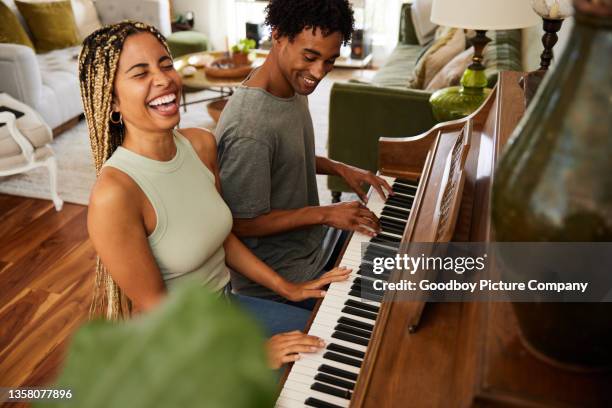 woman laughing while playing piano with her boyfriend at home - playing piano stock pictures, royalty-free photos & images