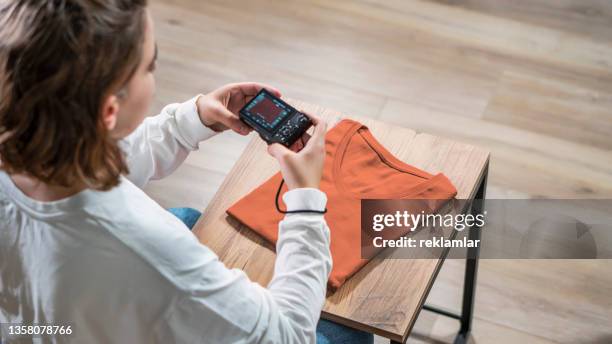 top view of a young female who is shooting an orange t-shirt to sell it as second hand. - obsolete stock pictures, royalty-free photos & images