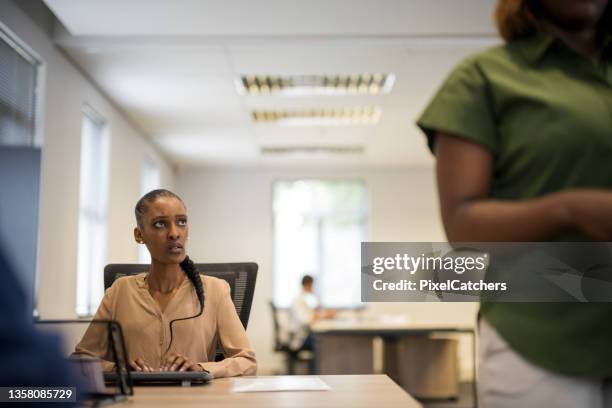 young woman looks upset at coworker throwing documents on her desk - upset coworker stock pictures, royalty-free photos & images